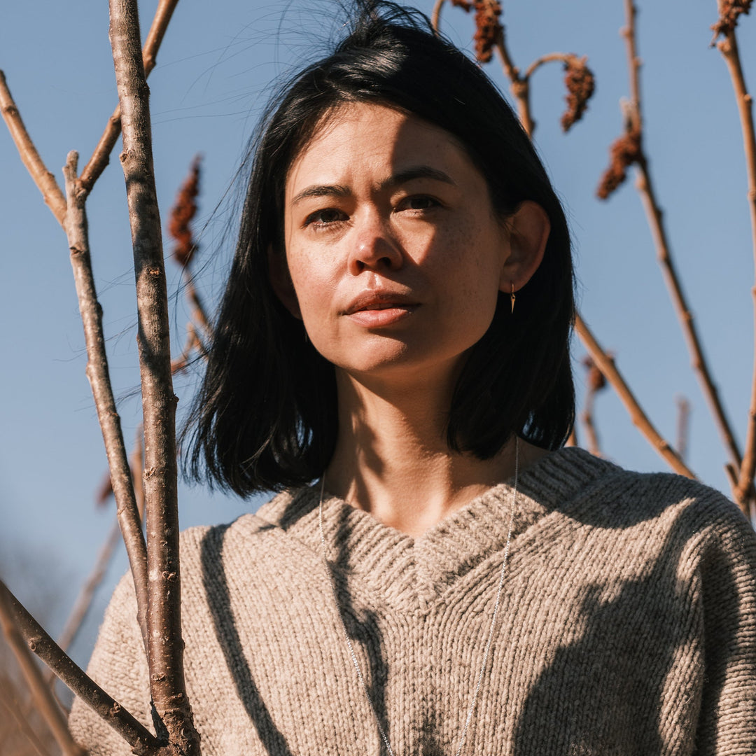 model wearing catbrier thorn earrings and sweater surrounded by sumac