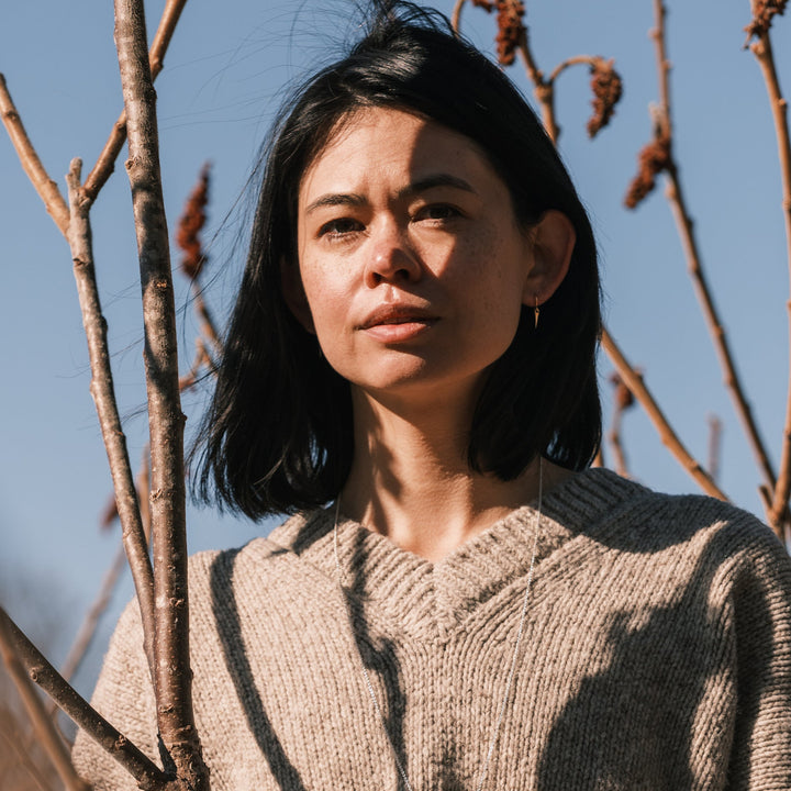 model wearing catbrier thorn earrings and sweater surrounded by sumac