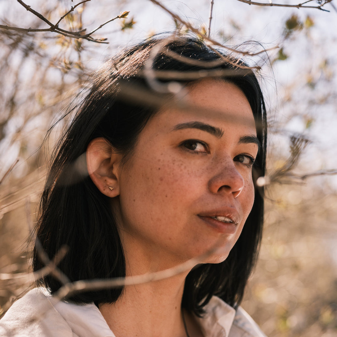 model wearing tiny vertebra stud earrings surrounded by lilacs