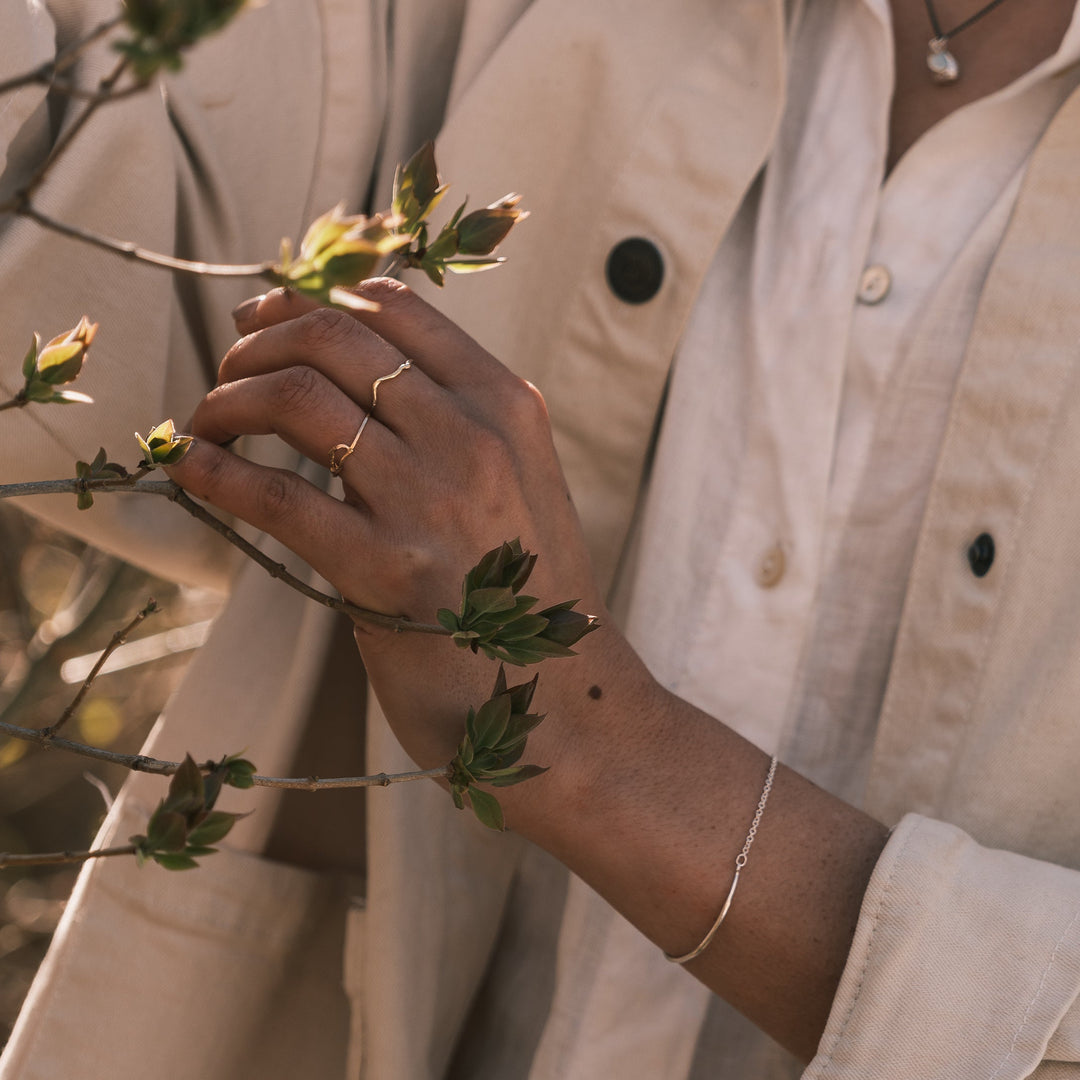 close up of model wearing robin nest twig ring holding lilac branch