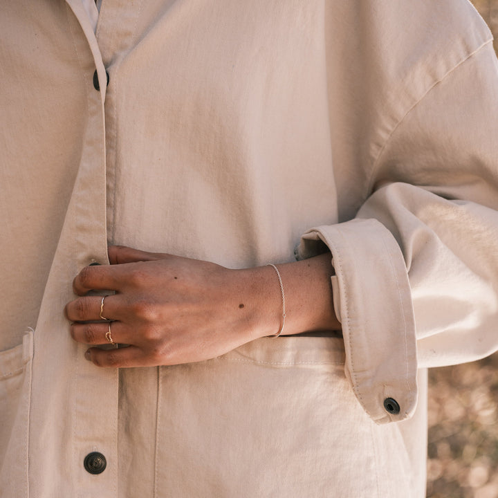 model wearing gold robin nest twig ring holding onto white jacket
