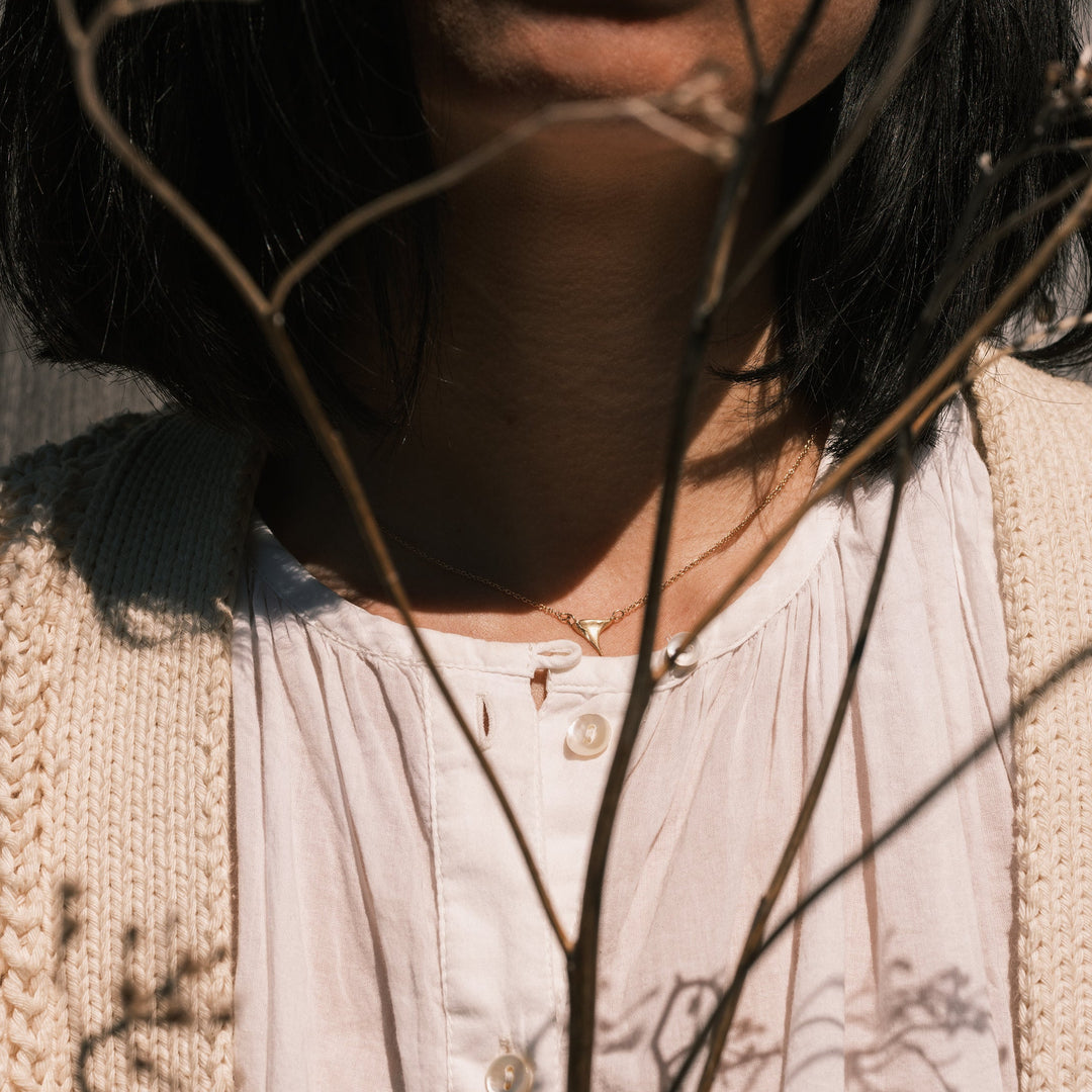 gold wild rose thorn necklace worn with white shirt and white sweater