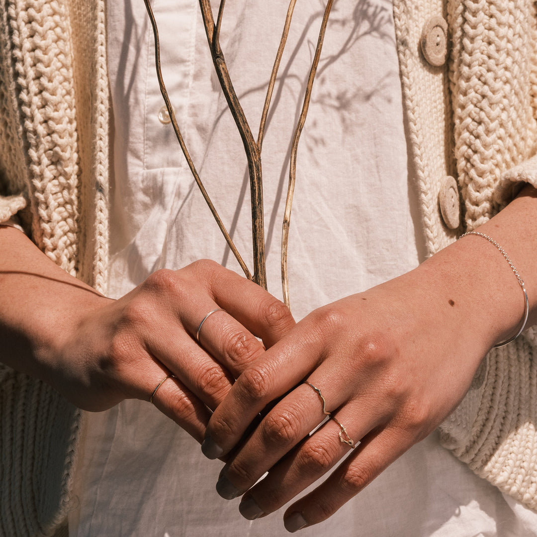 close up of model wearing robin nest twig ring holding dried goldenrod
