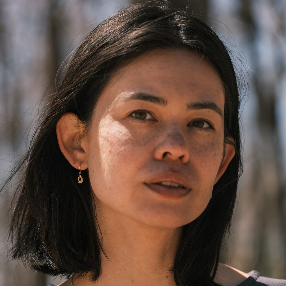 model wearing gold calendular seed earrings
