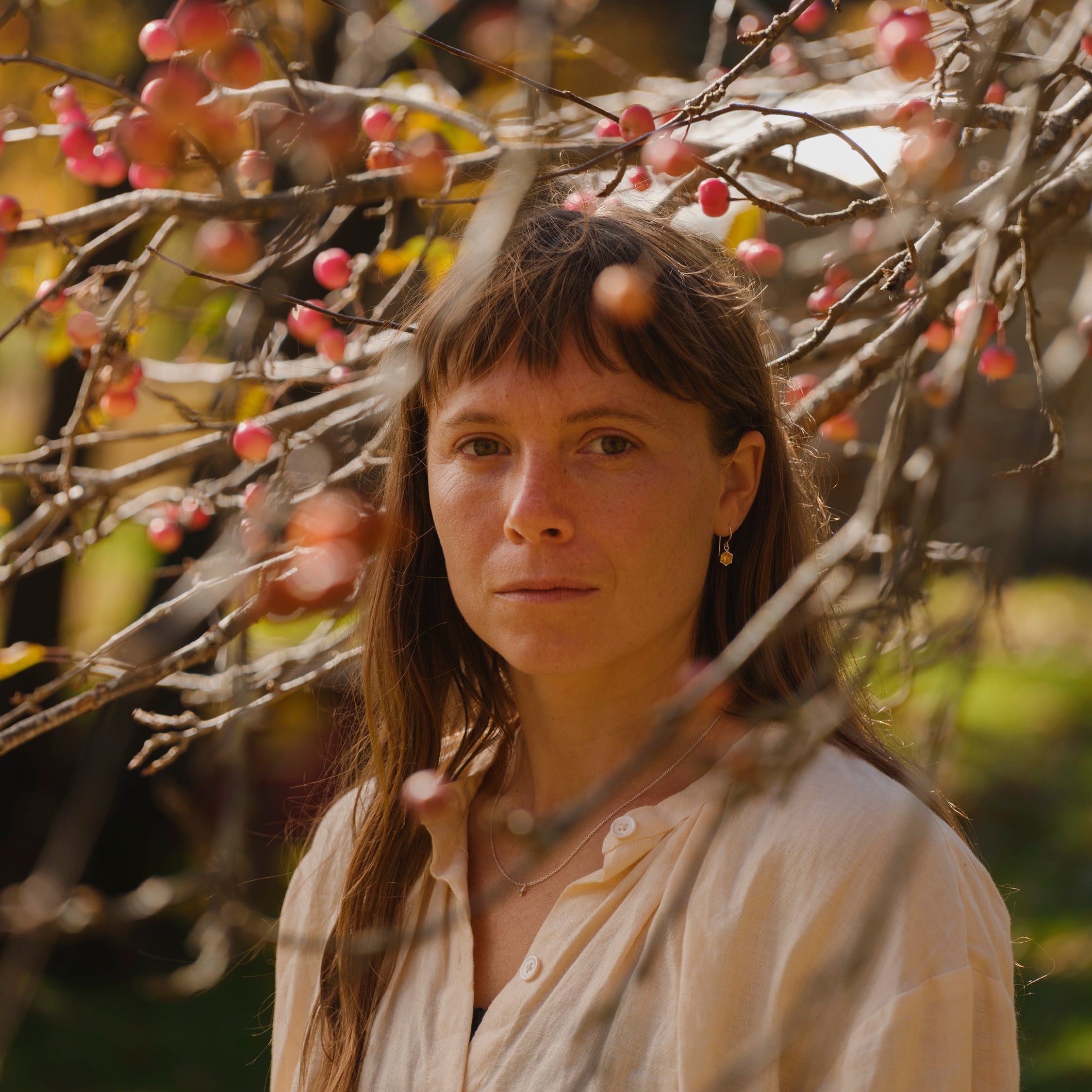 Model standing in front of a tree with fruit, blurred background